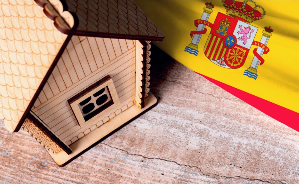 تصویری از ماکت خانه در کنار پرچم اسپانیا برای عنوان مهاجرت به اسپانیا از طریق خرید ملک انتخاب شده است.