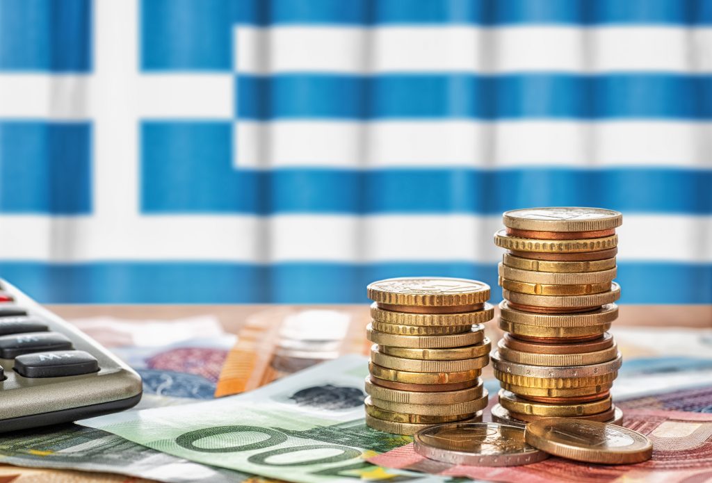 تصویری از سکه در مقابل پرچم یونان برای عنوان میزان درآمد در یونان انتخاب شده است.