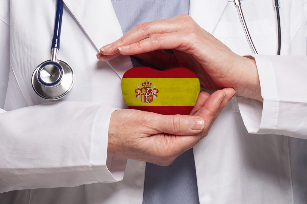 تصویری از پرچم اسپانیا به شکل قلب در دستان یک پزشک برای عنوان سیستم مراقبت‌های بهداشتی انتخاب شده است.