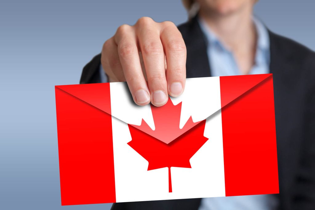 تصویری از پاکت نامه با طرح پرچم کانادا در دست یک فرد برای عنوان نامه اجازه تحصیل مدرسه در کانادا انتخاب شده است.