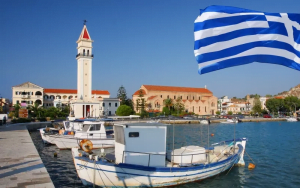 تصویری از زیبایی یونان در کنارپرچم آن به عنوان تصویر شاخص برای مطلب مزایا و معایب مهاجرت به یونان انتخاب شده است.