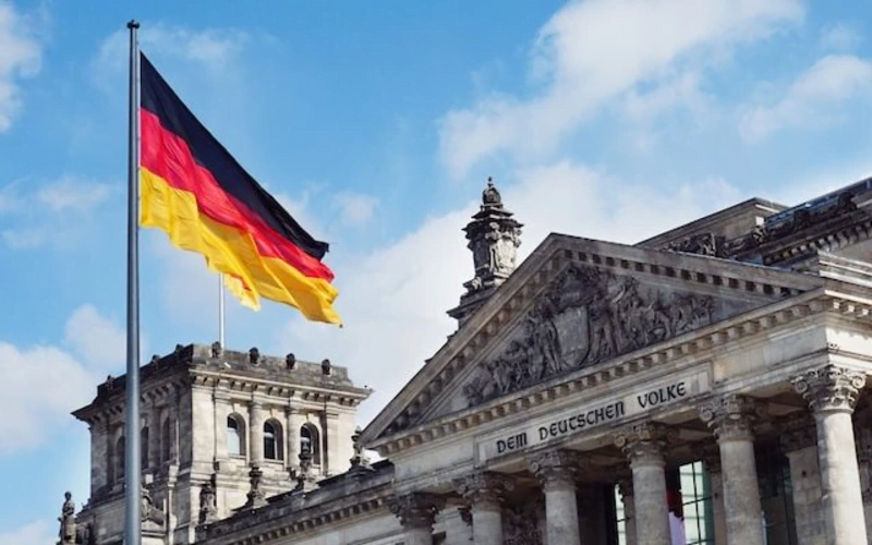 تصویری از پرچم آلمان در مقابل ساختمان اصلی این کشور برای عنوان مهاجرت به آلمان از طریق پناهندگی انتخاب شده است.